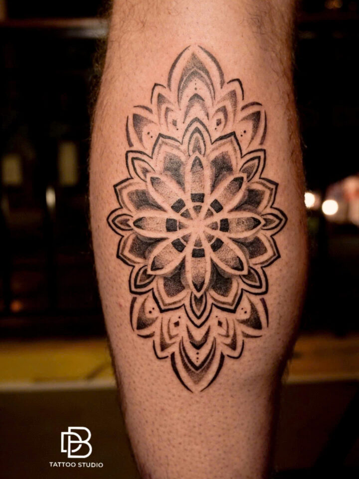 Black and grey dotwork mandala tattooed on the back of a calf