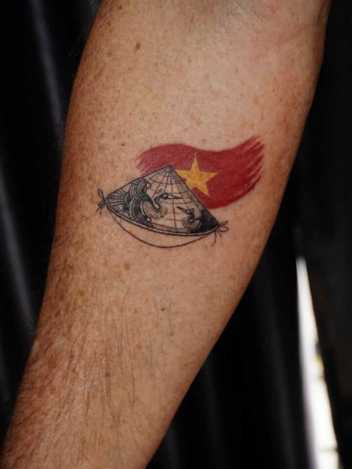 Small conical hat and Vietnamese flag tattoo on a forearm