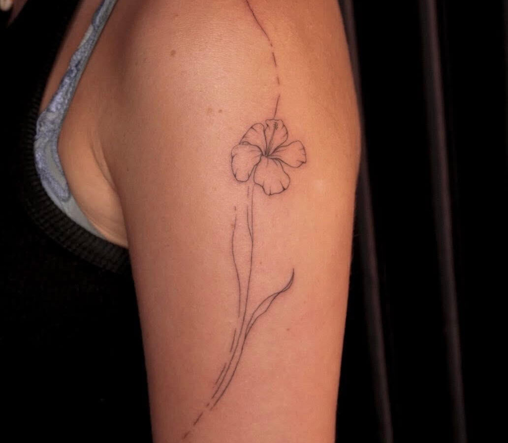Fine line flower tattooed down an upper arm