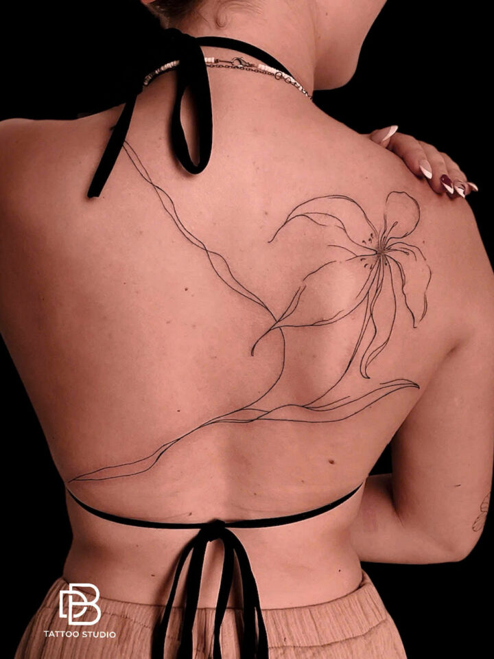 Single line lily tattooed across a bare back