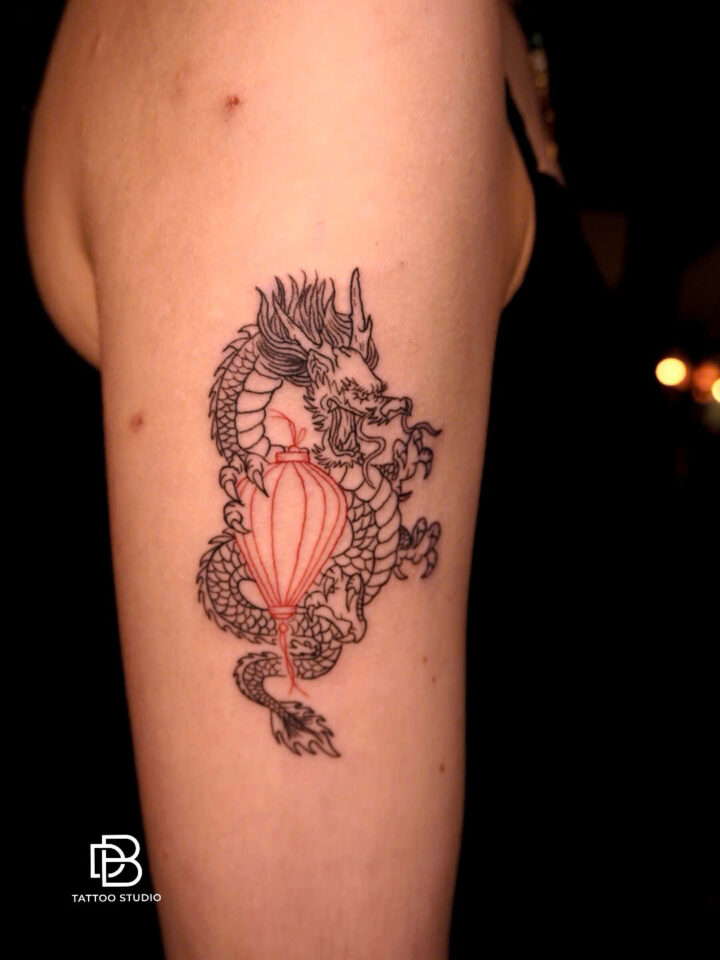 Mini dragon and red lantern tattoo on an upper arm
