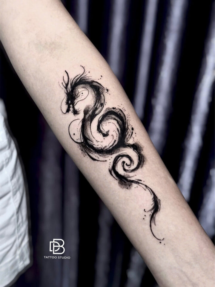 Brush stroke ink dragon tattooed along a forearm