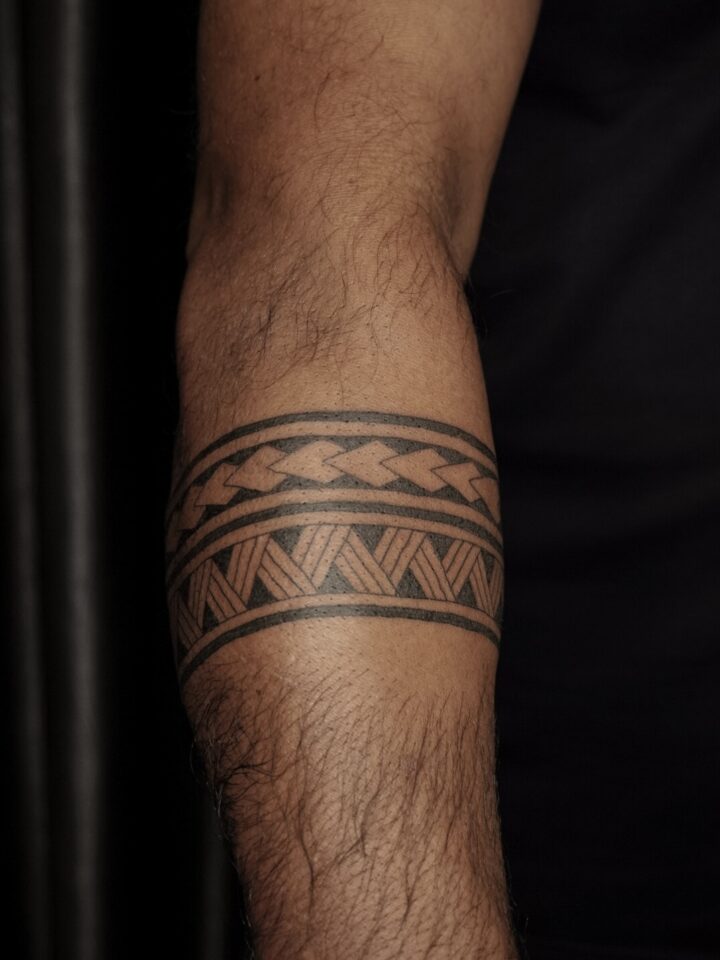 Polynesian armband tattoo around a forearm