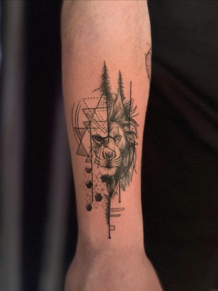 Geometric wolf head with pine trees and dotwork on a forearm