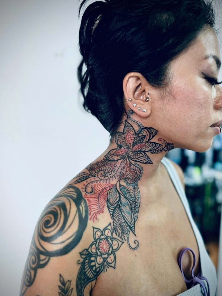 Ornamental floral neck and shoulder tattoo with red ink accents