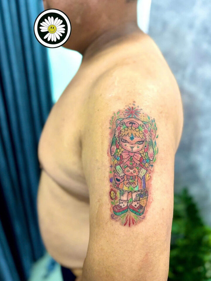 Bright colour ornamental totem figure tattooed on an upper arm
