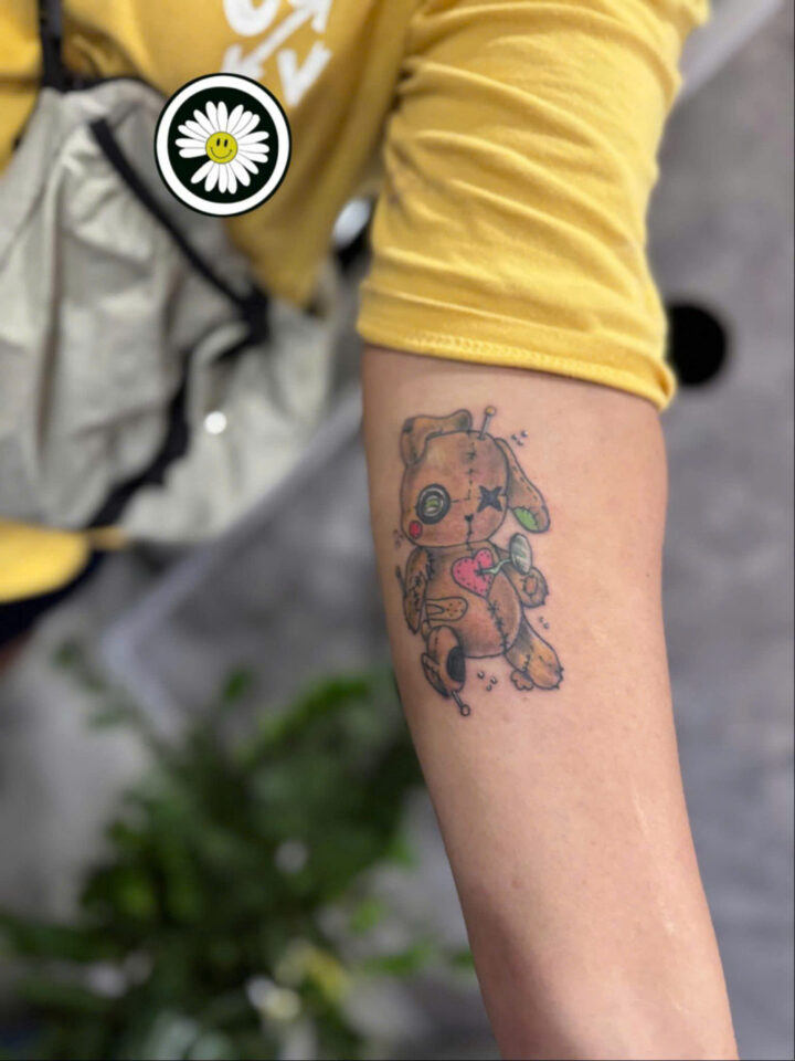 Soft colour cartoon dog tattooed on an upper arm