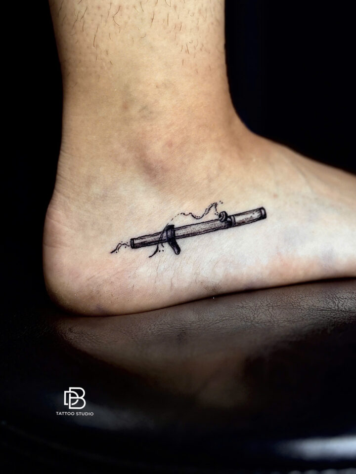 Black and grey bamboo flute tattooed along the ankle