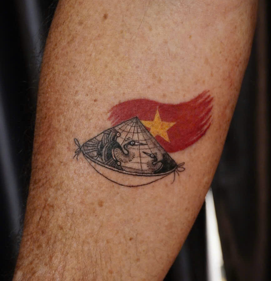 Non la conical hat tattooed over the red Vietnamese flag on a forearm