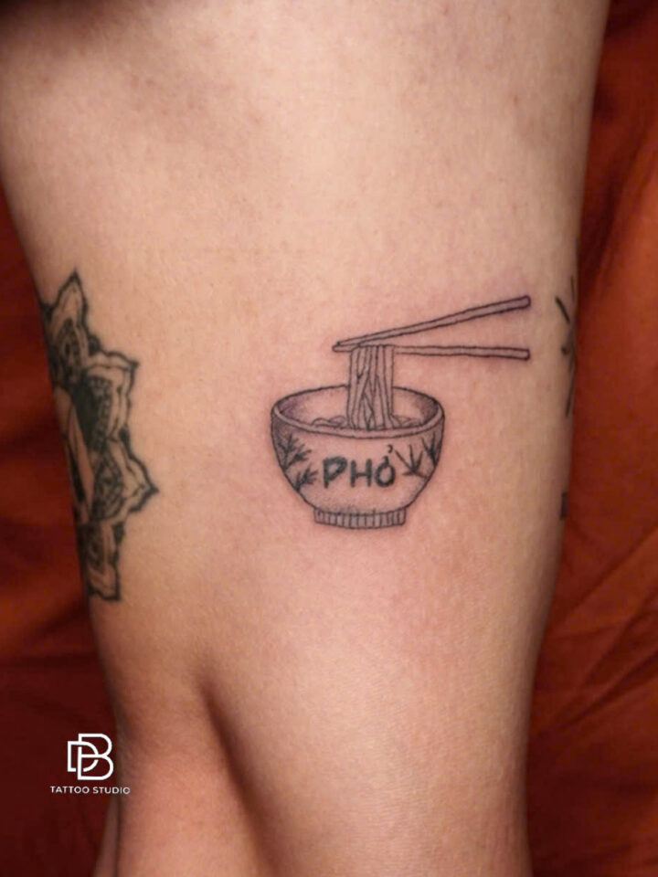 Black and grey tattoo of a bowl of pho with chopsticks on a thigh