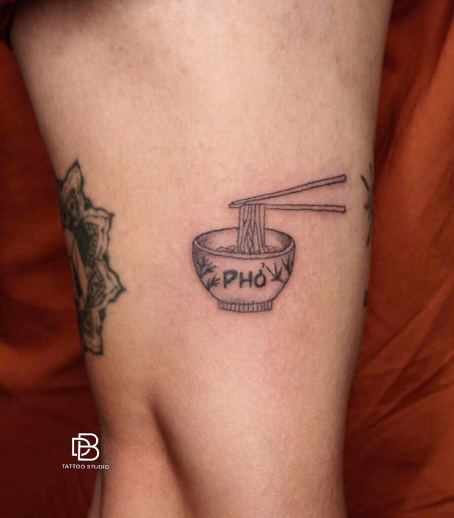 Black and grey tattoo of a bowl of pho with chopsticks on a thigh