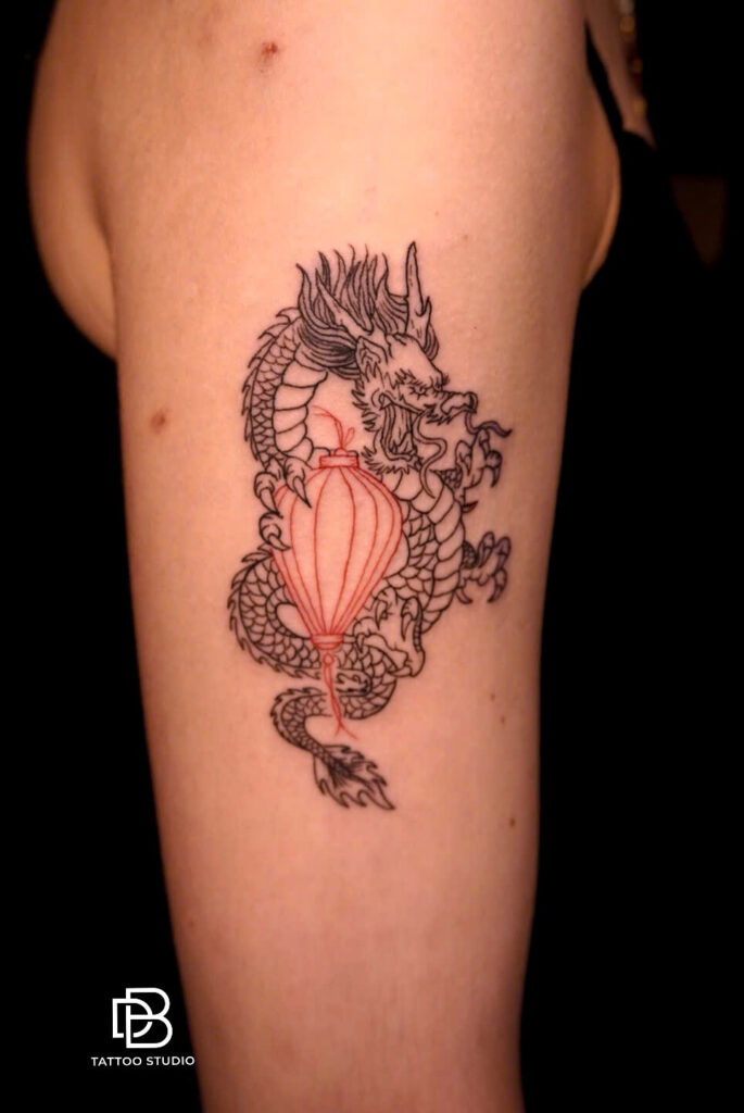 Vietnamese dragon coiled around a red Hoi An lantern, tattooed on an arm