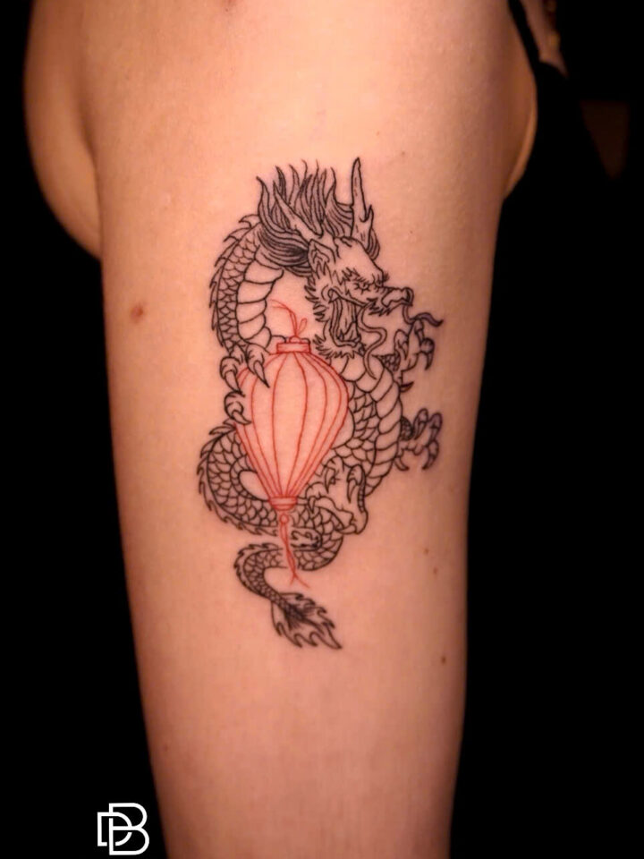 Vietnamese dragon coiled around a red Hoi An lantern, tattooed on an arm
