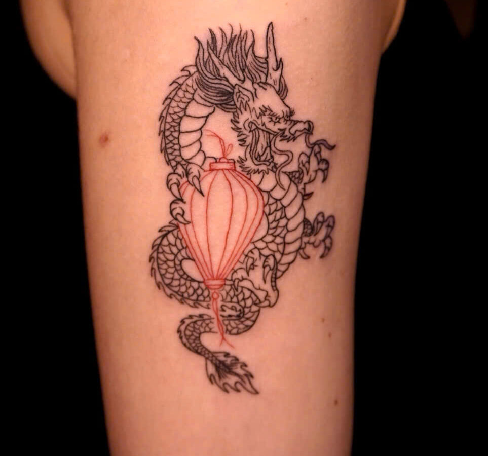 Vietnamese dragon coiled around a red Hoi An lantern, tattooed on an arm