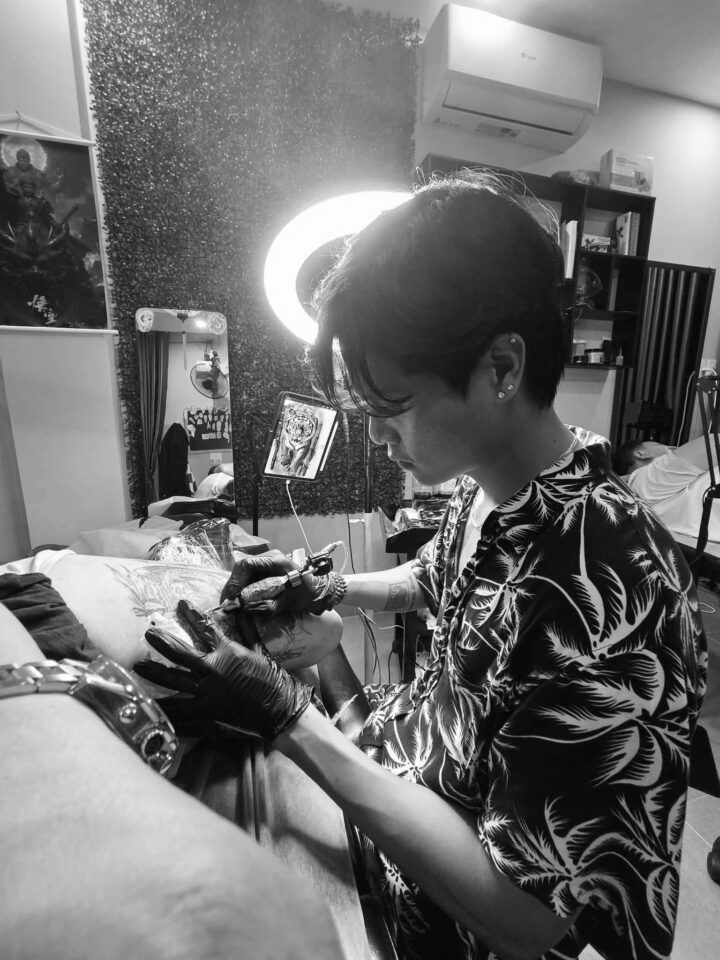 Tattoo artist working under a ring light at DanBam Tattoo Studio