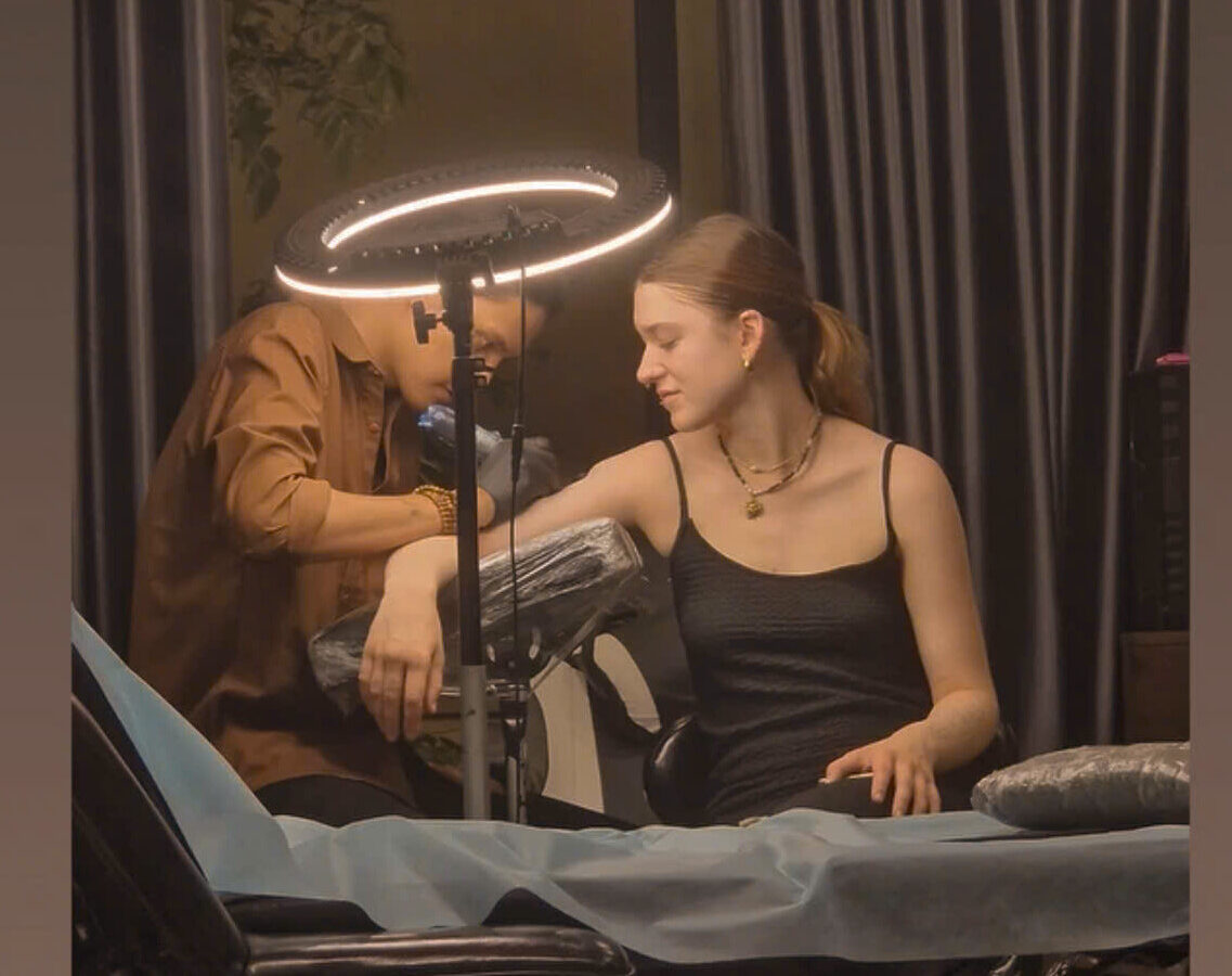 An artist tattooing a client under the ring light at the DanBam studio