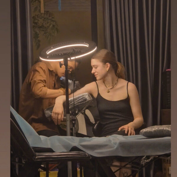 An artist tattooing a client under the ring light at the DanBam studio