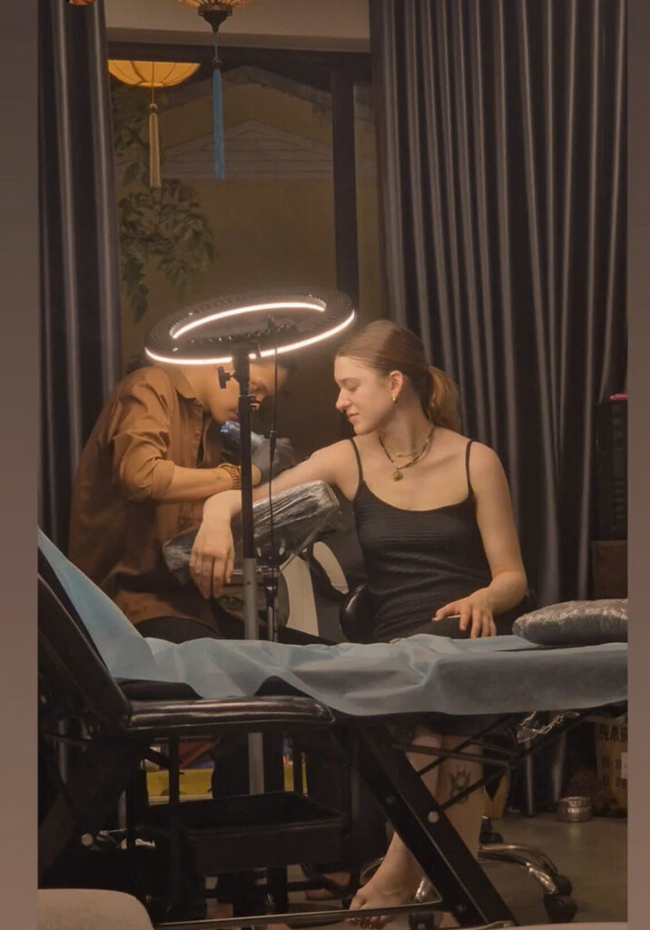 An artist tattooing a client under the ring light at the DanBam studio