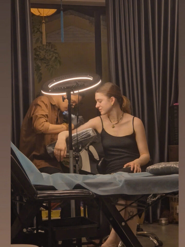 An artist tattooing a client under the ring light at the DanBam studio